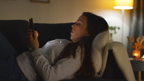 Close-Up-Of-Woman-Lying-On-Sofa-At-Home-At-Streaming-Or-Watching-Movie-Or-Show-Or-Scrolling-Internet-On-Mobile-Phone-8